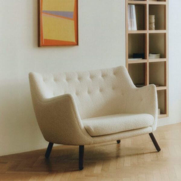 Finn Juhl poet sofa i udstilling med billede i baggrunden og indbygget reol i vægen